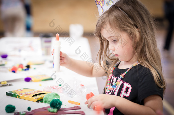 little girl making handcraft at a table