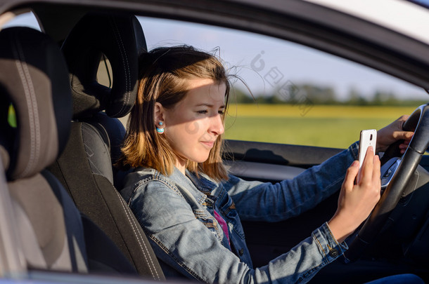 Young female driver reading a text message