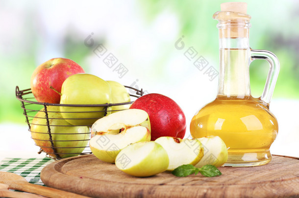 苹果醋玻璃瓶和成熟的新鲜苹果，木制的桌子，对自然背景上
