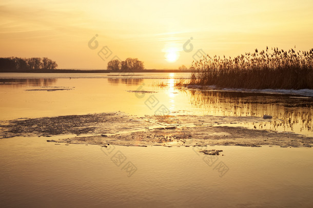 冬季景观与河流、 芦苇和日落天空.