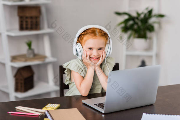 小女孩用耳机和笔记本电脑
