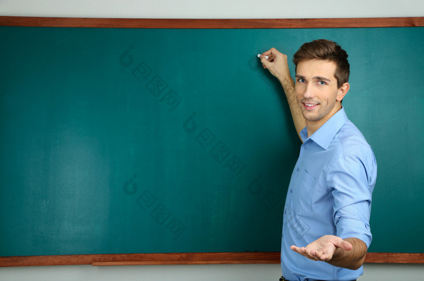 附近学校的教室的黑板上的年轻老师