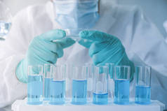 亚洲科学家致力于蓝色试管，在实验室或实验室的技术、医疗、化学、保健和研究概念中分析和开发Covid-19病毒疫苗。实验科学