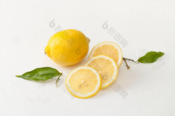 白色混凝土背景上的柠檬叶和切碎的柠檬片.