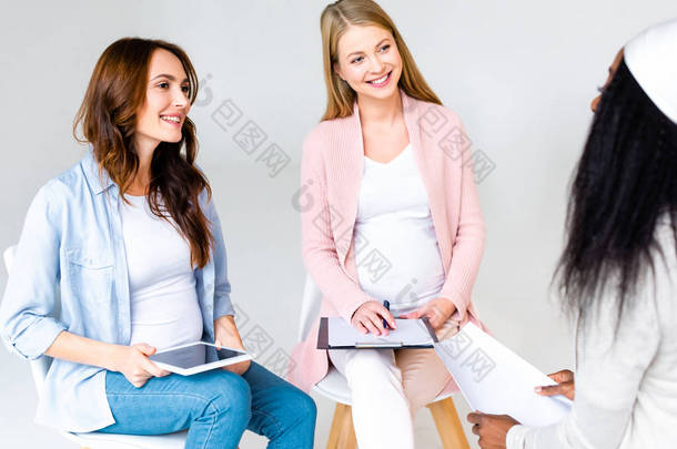 多元文化的孕妇在与灰色隔离的班级会议时交谈