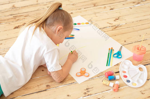 女孩躺在地板上绘画用品和绘画在<strong>白纸</strong>上