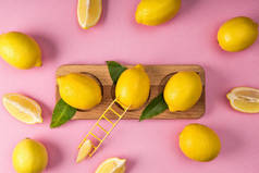 粉红色背景上小梯子的木木板上鲜黄色柠檬的顶部视图 