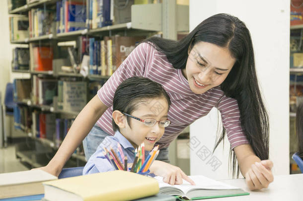 女教师和儿童学生在书架背景下学习书籍