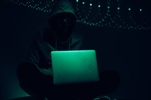 用膝上型电脑在帽衫中的黑客剪影的色调<strong>图片</strong>
