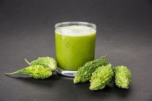 在蔬菜切片，karela 果汁或苦瓜汁一杯绿色 momodica 的草药汁