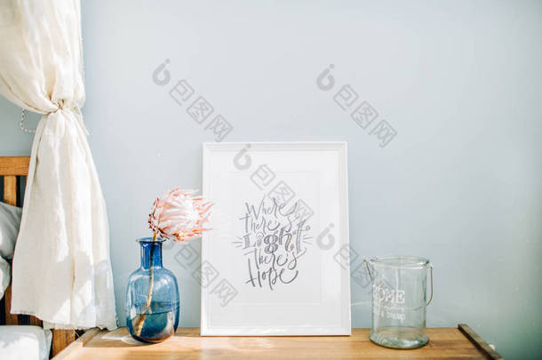 相框与书法报价那里有光明有希望, 普罗蒂亚花在花瓶前面的粉彩蓝墙。模拟帧.