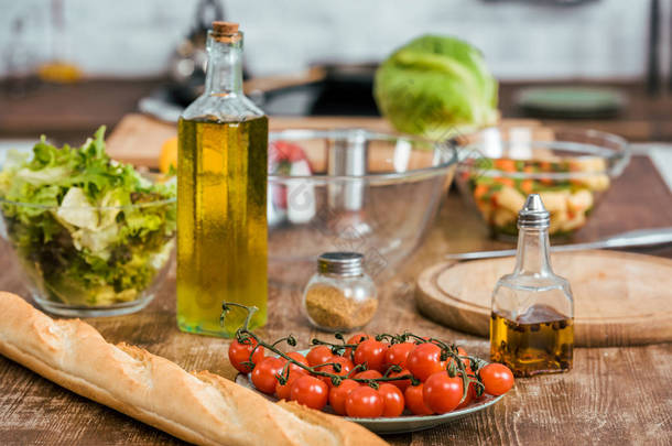 在厨房的桌面上的沙拉, 瓶橄榄油和长方形的成熟新鲜蔬菜