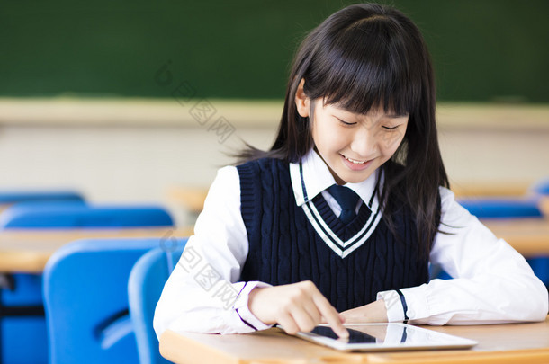 快乐漂亮的学生女孩在教室里的平板电脑