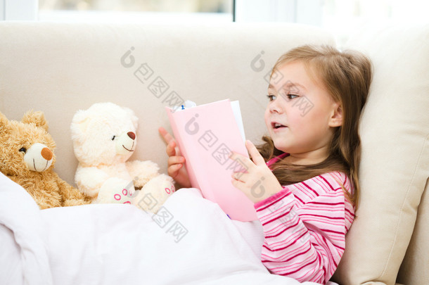 小女孩她的<strong>玩具熊</strong>读一本书