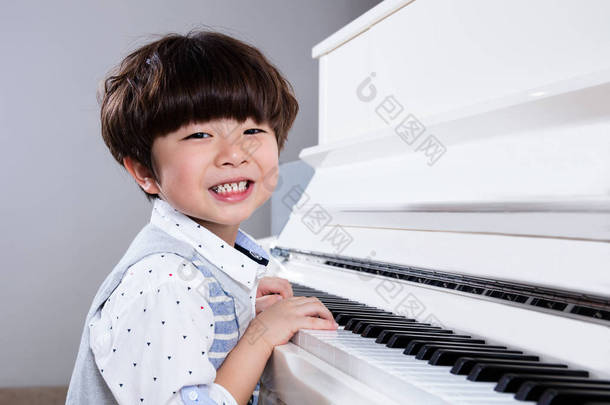 <strong>快乐</strong>亚洲中国小男孩在家里弹钢琴