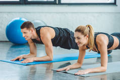 夫妇在健身房锻炼前在垫子上做腹肌练习