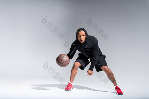 运动的非洲裔美<strong>国人</strong>男子打篮球球和看在灰色相机 