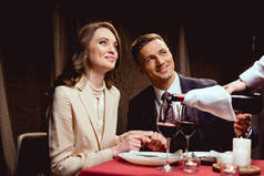 服务员倒红酒, 而微笑的夫妇有浪漫的约会在餐厅