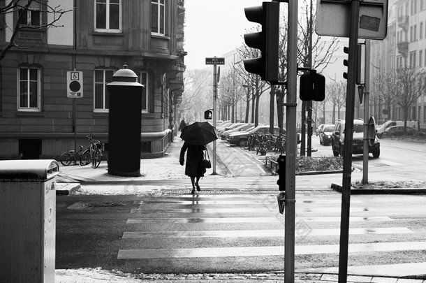 Old woman with umbrella crossing street