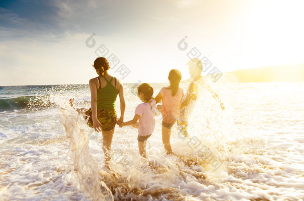 在日落时在沙滩上玩的快乐年轻家庭