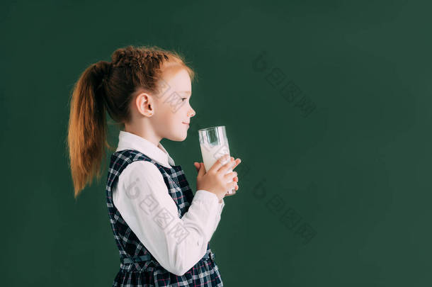 站在黑板边的微笑小女生的侧面看着玻璃牛奶