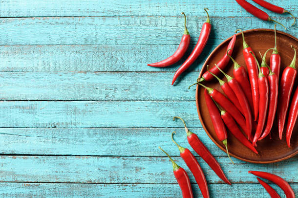 红色成熟辣椒在板材和蓝色木桌上的高的看法