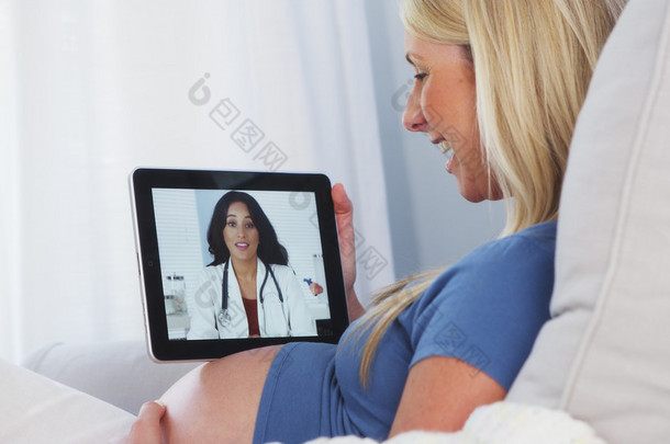 怀<strong>孕</strong>的女人跟她的医生在平板电脑上