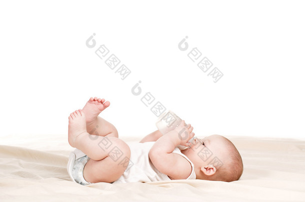 可爱的婴儿，用一瓶牛奶在米色的毛毯