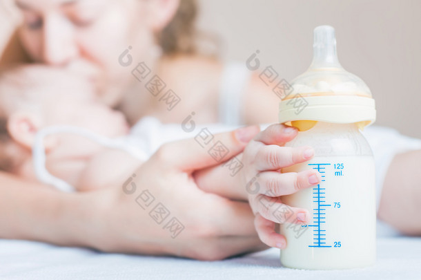 Baby holding a baby bottle with breast milk