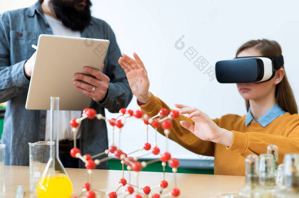 年轻教师使用虚拟现实眼镜和3d演示,教授学生在化学课教育Vr辅导新技术与教学方法理念.