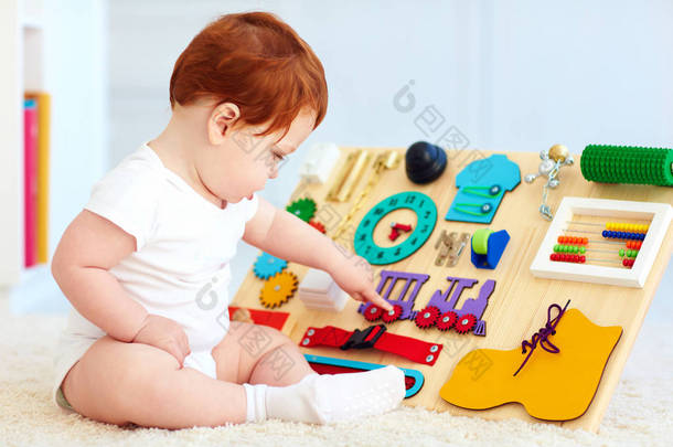 可爱的蹒跚学步婴儿玩忙板在家里