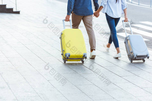 两个游客牵着手提着行李