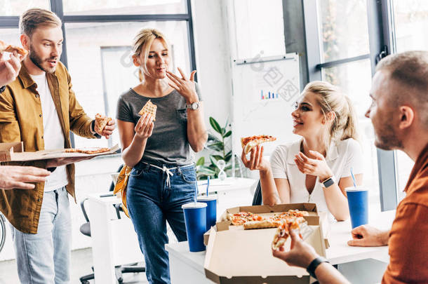 一组成功的企业家在办公室开始工作时一起吃披萨午餐