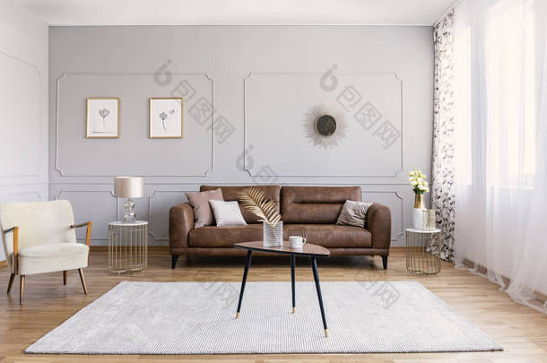 简约的室内设计, 配有棕色真皮沙发、复古扶手椅咖啡桌和金色装饰品、真实照片
