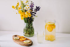 夏天的概念。野生自然花卉的花束。自制柠檬水与橙子和柠檬。健康的新鲜冷饮 