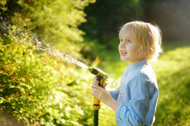 有趣的小男孩在阳光灿烂的后院浇灌植物，玩花园软管和洒水。学龄前<strong>儿童</strong>与喷水为乐.青少年<strong>暑期</strong>户外活动.