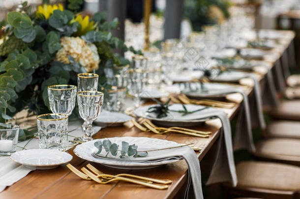 用叉子和勺子装饰的盘子。桌子采用波西米亚风格，并配有潘帕斯草和绿色植物