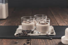 一杯加冰块的奶油咖啡利口酒和咖啡豆，背景为质朴的木质。