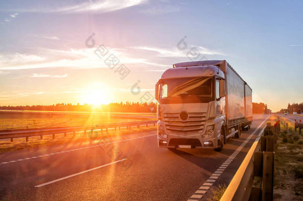 现代货车在日落的背景下运输货物。卡车司机的概念