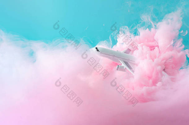 客机飞机玩具在柔和的粉红色云中飞行。旅游理念.