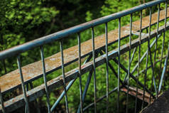 桥梁旧金属护栏, 背景模糊的绿色森林.