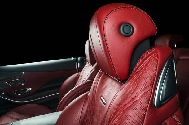 现代豪华车里面。内部的威望现代汽车。舒适的真皮红色座椅。红色穿孔皮革驾驶舱与孤立的黑色背景。现代汽车内饰细节