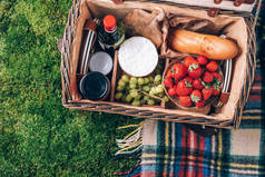 带有水果、奶酪、蜂蜜、草莓、葡萄、面包、葡萄酒和柳条筐的野餐用的野餐用的皮卡，上面铺着青草。顶部视图。复制空间。夏季野餐时间，家庭午餐。浪漫的野餐.