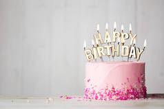 粉红色的生日蛋糕和金色的生日蜡烛