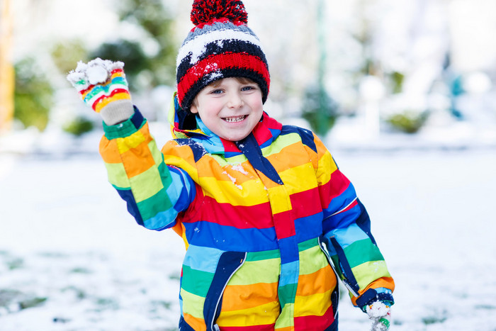 在丰富多彩的冬天的衣服出去玩堆雪人小男孩