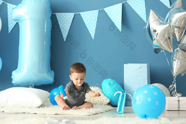 可爱的小男孩坐在地毯上装饰的第一个生日<strong>聚会</strong>的房间
