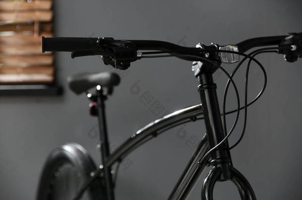 室内灰墙附近的现代<strong>黑色</strong>自行车，特写镜头