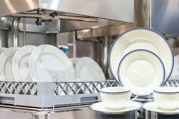 厨房餐厅用自动洗碗机洗碗的盘子杯和篮子上的许多白盘