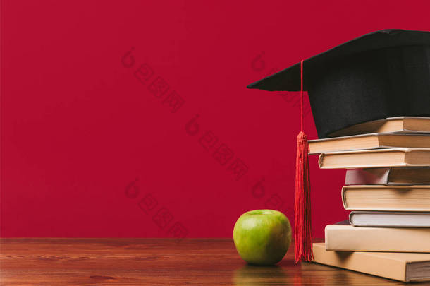 顶部有学术帽的书和苹果的<strong>红色</strong>的裁剪视图