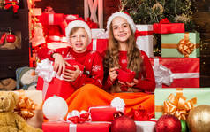 孩子们，快乐的小女孩和男孩在圣诞树旁找到了礼物。圣诞快乐。祝你圣诞快乐。发现冬天的美丽。热可可。礼品店。小孩子的圣诞礼品盒。休闲和愉快的放松